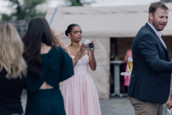 Woman in pink takes picture on polaroid camera