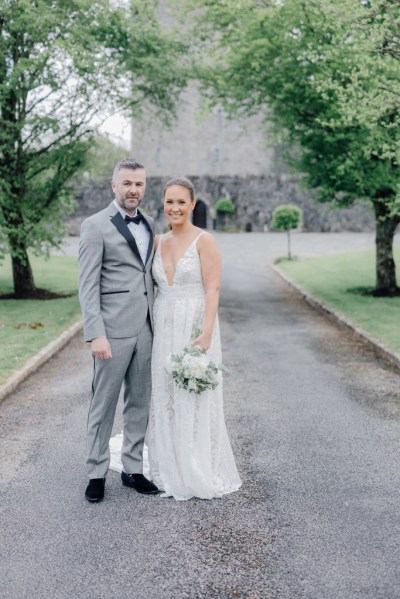 Bride holds bouquet and poses with groom on pathway