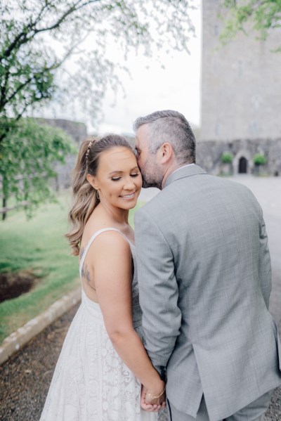 Groom kisses brides cheek as she looks over shoulder