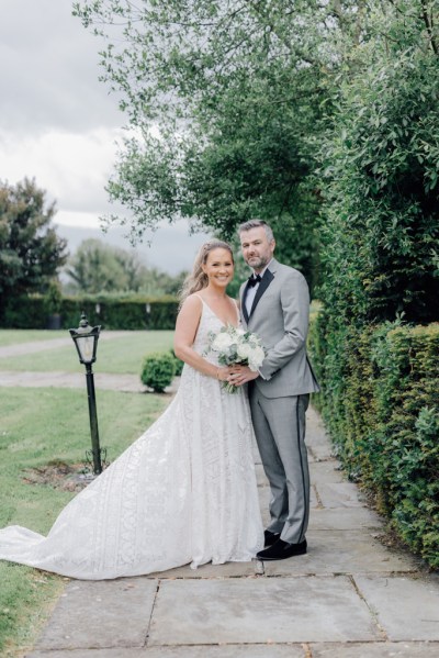 Bride and groom stand on pathway in garden