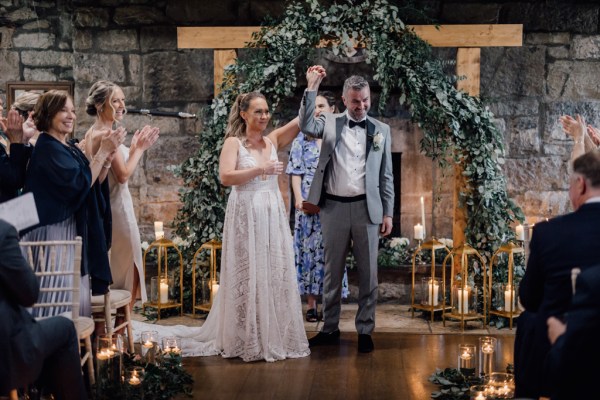 Bride and groom at alter to ceremony hands in the air