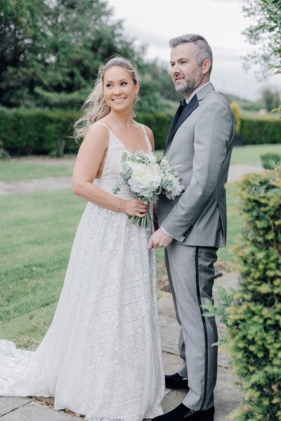 Bride and groom pose on the grass exterior shot