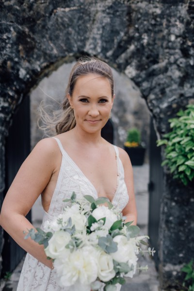 Bride on her own poses holding bouquet