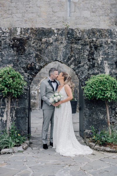 Bride and groom kiss under archway