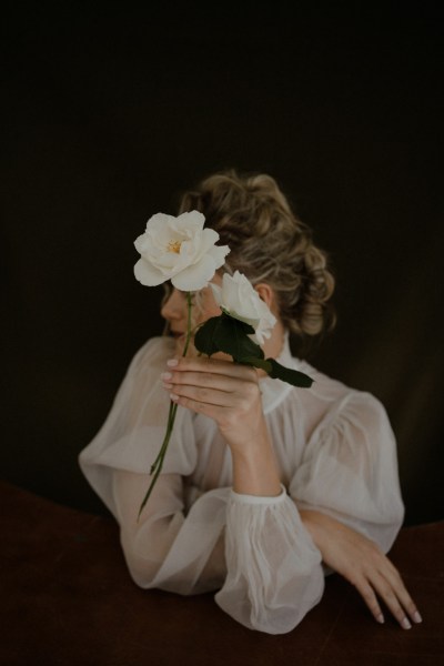 Dark photography bride holding white roses flowers hairdo curls blonde hair detail