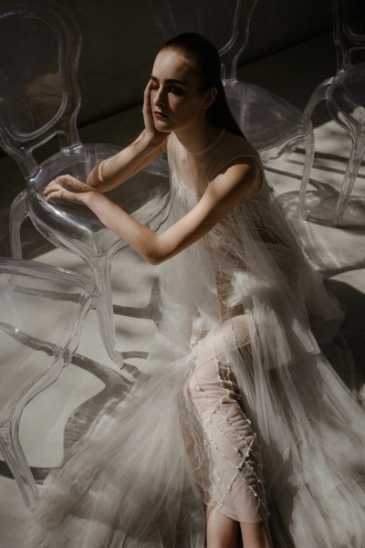 Bride sitting down leaning on plastic see-through chair