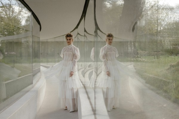 blonde curly haired woman wavy sitting against window relfection ruffle neckline bridal gown detail reflection