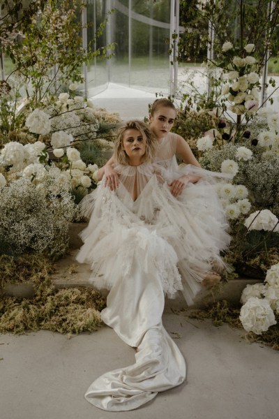 Brides models lies in a bed of flowers on the steps to greenhouse white roses