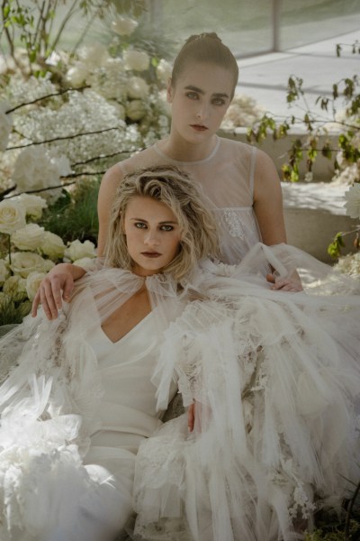 Brides models lies in a bed of flowers on the steps to greenhouse white roses