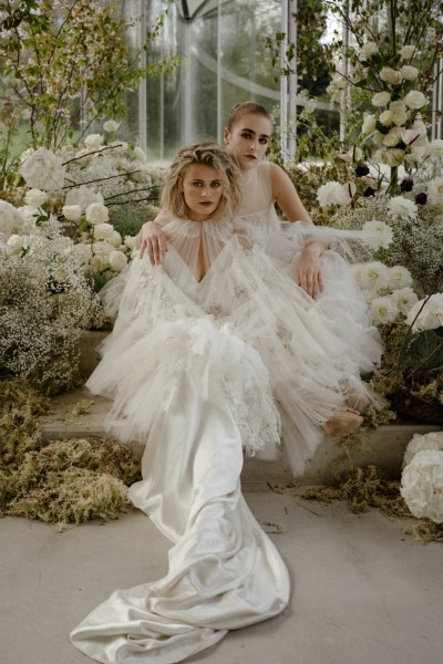 Brides models lies in a bed of flowers on the steps to greenhouse white roses