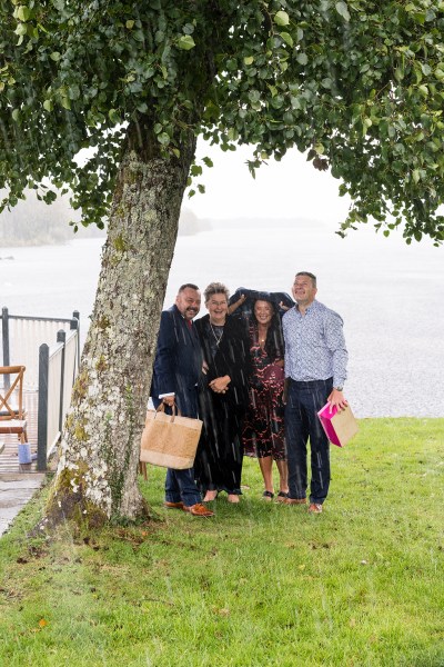 Family duck in under the rain coat over head under tree in front of lake setting