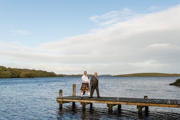 Grooms walk on boardwalk above lake setting