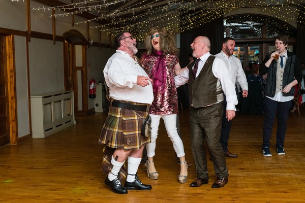 Man in kilt on dancefloor drag queen laughing