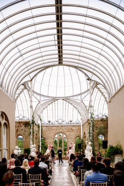 Bride and groom kiss kissing at alter in front of officiant guests in audience