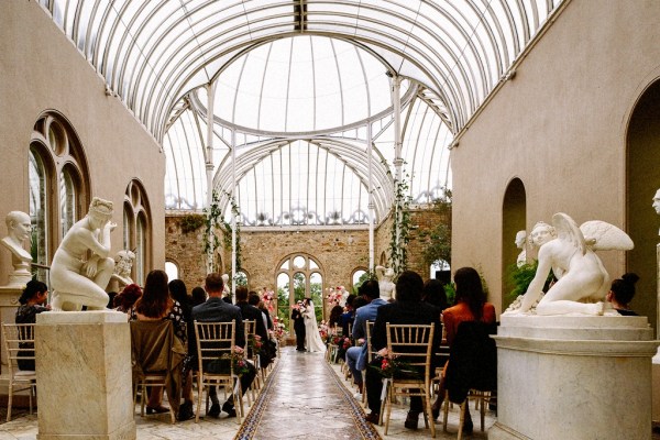 Bride and groom kiss kissing at alter in front of officiant guests in audience