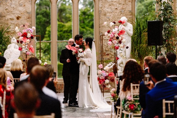 Bride and groom kiss kissing at alter in front of officiant