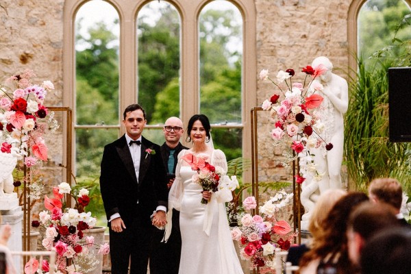 Bride and groom standing at alter together in front of guests with officiant