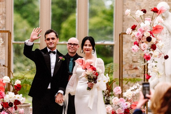 Bride and groom wave at alter in front of guests