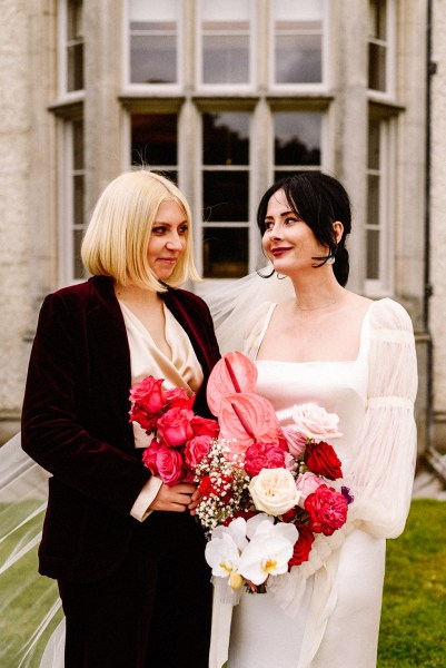 Bride and bridesmaid holding red pink roses flowers bouquet