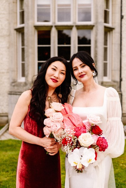 Bride and bridesmaid holding red pink roses flowers bouquet