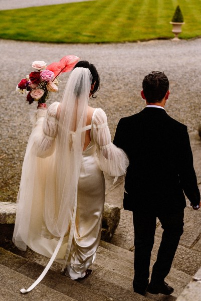 Bride and groom walk down the steps holding flowers/bouquet