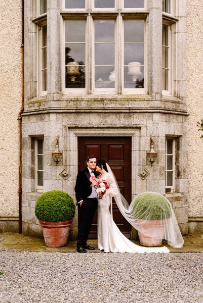 Couple bride groom looking at each other exterior wedding venue front door hugging