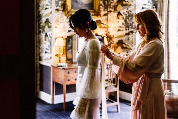 Bridesmaid or mother helping bride with dress/gown in bedroom