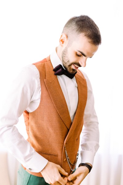 Groom in orange waistcoat looks down