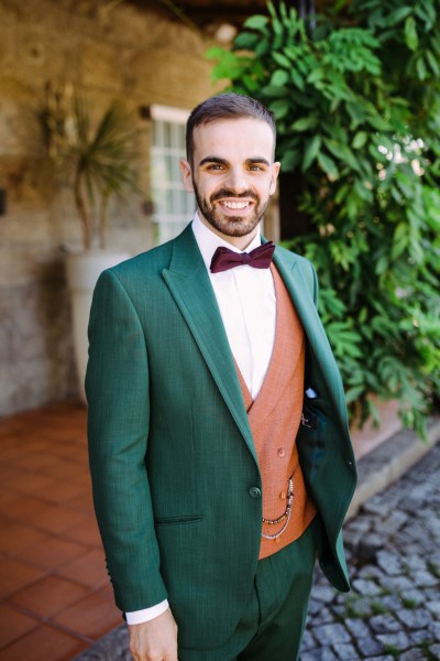 Groom in green and orange waistcoat getting ready smiles