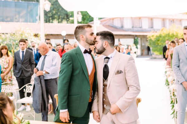 Groom kisses groom on forehead at alter