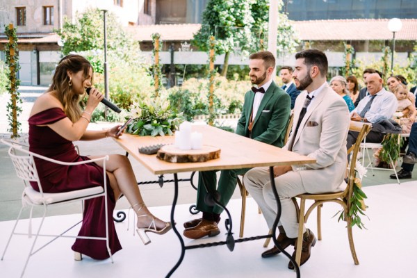 Officiant speaking into microphone in front of grooms sitting