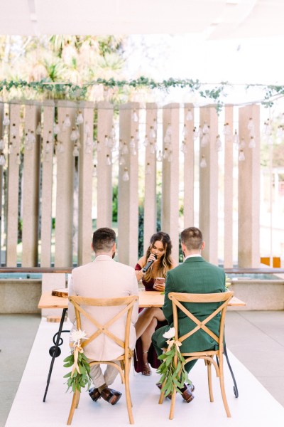 Officiant speaking into microphone in front of grooms sitting