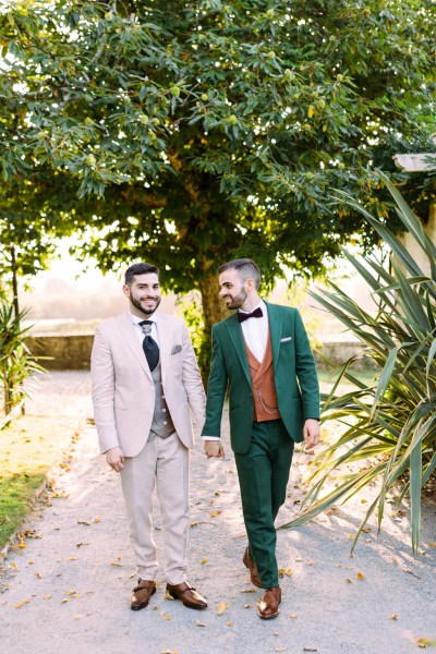 Groom looks at groom as they walk along pathway