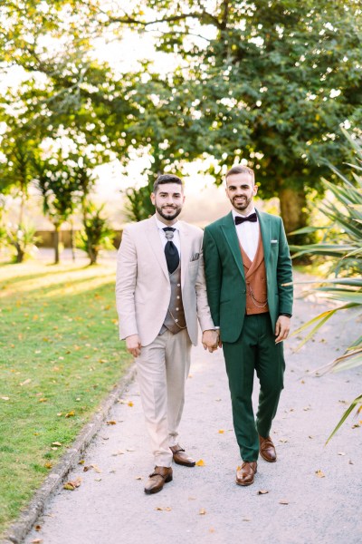 Grooms walk hand in hand along pathway