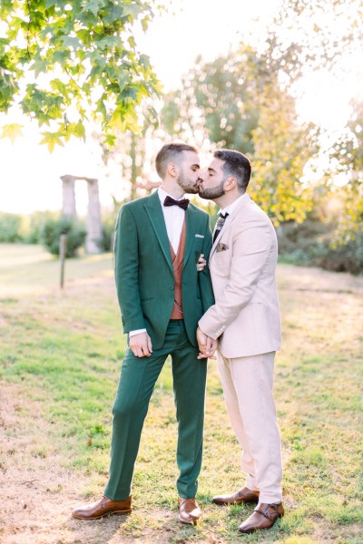 Grooms kiss in garden holding hands