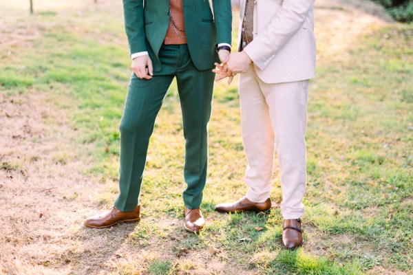 Grooms holding hands in garden close up