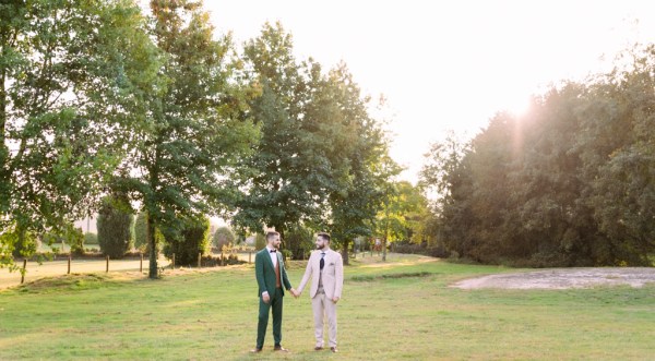 Grooms holding hands in garden