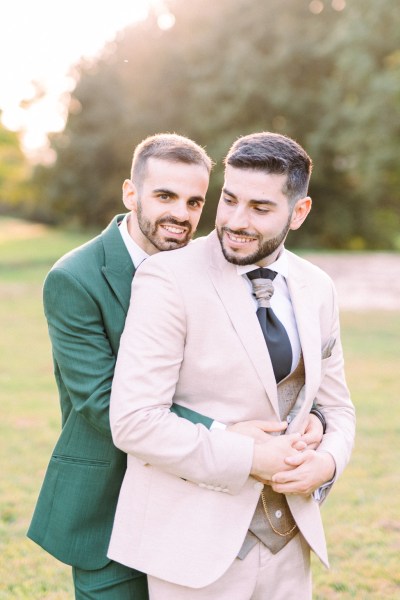 Groom hugs groom from behind in park garden