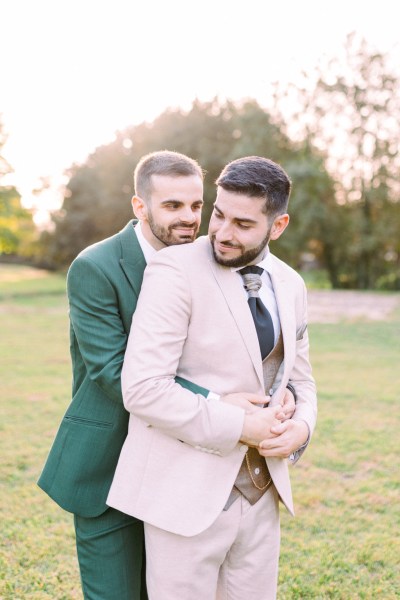 Groom hugs groom from behind in park garden