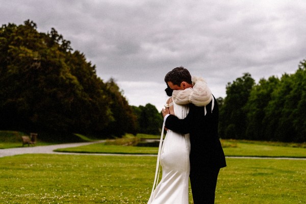 Bride approaches groom in garden grass in background they embrace on steps close up