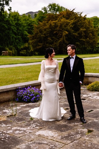 Bride and groom hand in hand holding hands in garden