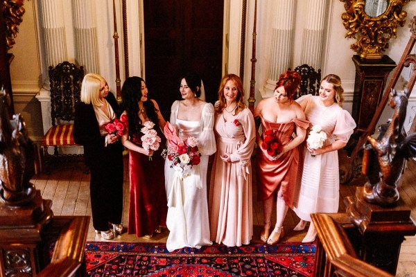 Interior shot of bridesmaids and bride on red carpet rug stately home interior setting