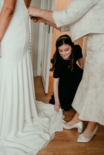 Bridal gown from behind bridesmaid helps with dress