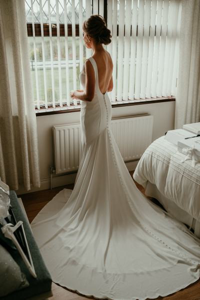 Long dress train detail bride stands at window