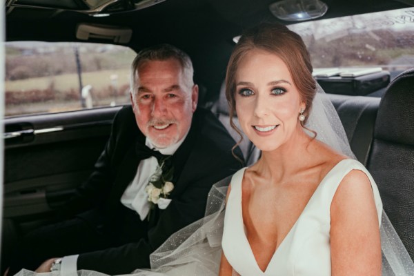 Black and white image of bride and father in wedding car veil detail