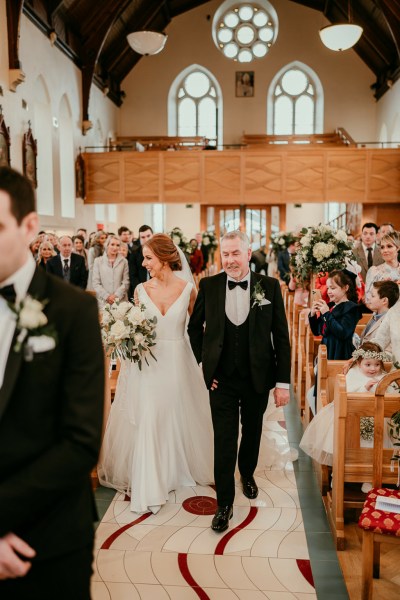 Father of the bride walks down the aisle smiling