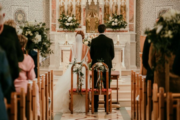 Bride and groom standing in front of priest at alter