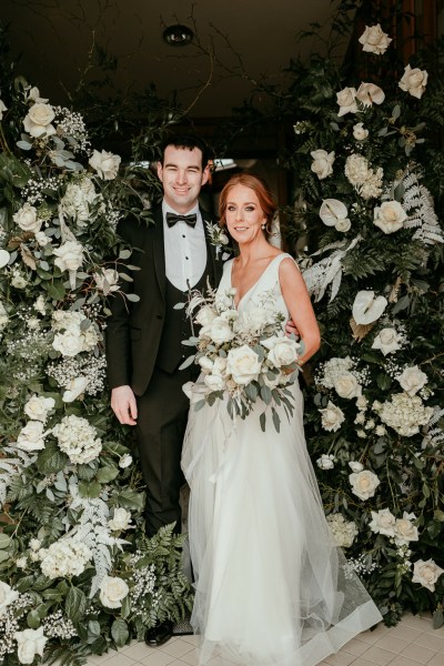 Bride and groom kissing surrounded by bed of flowers roses white bouquet