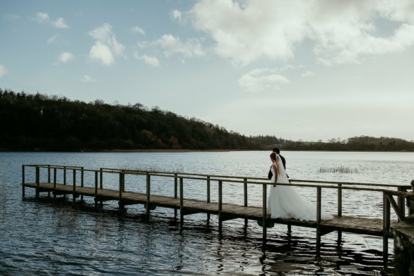 Bride and groom walk on the boardwalk towards lake