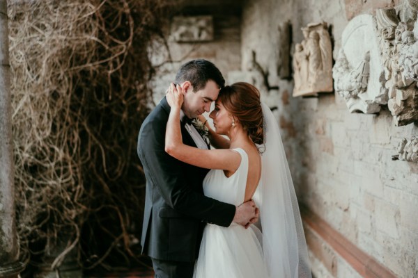 Bride on groom stand on checkered floor old rustic vibe embracing